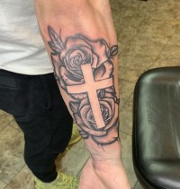 A black and white tattoo of a cross over two roses