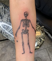A black and white tattoo of a smiling skeleton