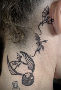 illustrative black and grey tattoo of a golden snitch and tiny game of thrones dragons