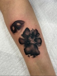 Black and grey tattoo of a nose print and dog paw print