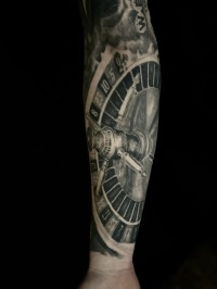 a realistic black ink tattoo of a roulette wheel