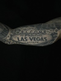 a black ink tattoo of the famous "Welcome to Fabulous Las Vegas Nevada" sign