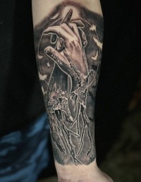 a black ink tattoo of interlocking severed hands with roots growing out of the arm