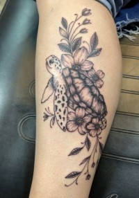 A black and white tattoo of a collage of a sea turtle and flowers