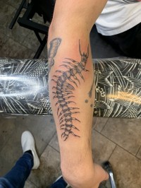 A black and white tattoo of a giant centipede