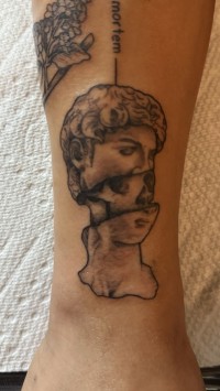 a tattoo of a Greek statue head pulled apart to reveal a skull