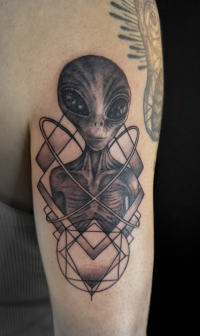 illustrative black and grey tattoo of an alien