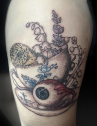 illustrative black and grey tattoo with small amount of color of a teacup with a lizard and flowers