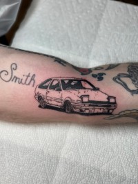 Tattoo of a drawing of an 80's car with pop-up headlights