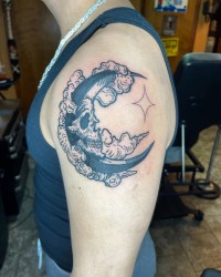 Tattoo of a drawing of the moon with a skull face