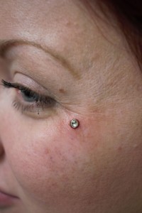 A woman with a teardrop dermal piercing under her eye