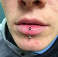 A man with a vertical labret piercing in his lower lip