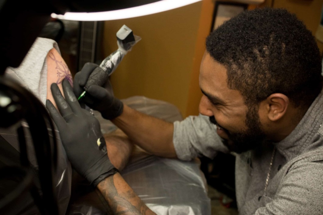 A man tattooing another man's arm